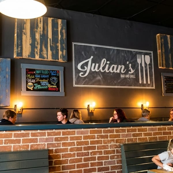 Diners seated in booths at Julian's Bar and Grill, with a large sign and artwork on the wall.