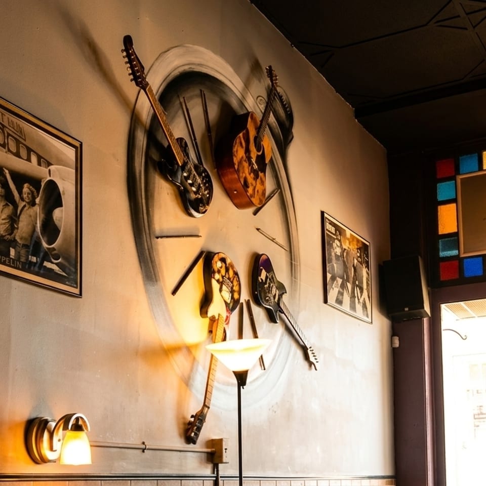 Wall decor with Led Zeppelin poster, guitars, and a stained glass window with a hanging lamp.