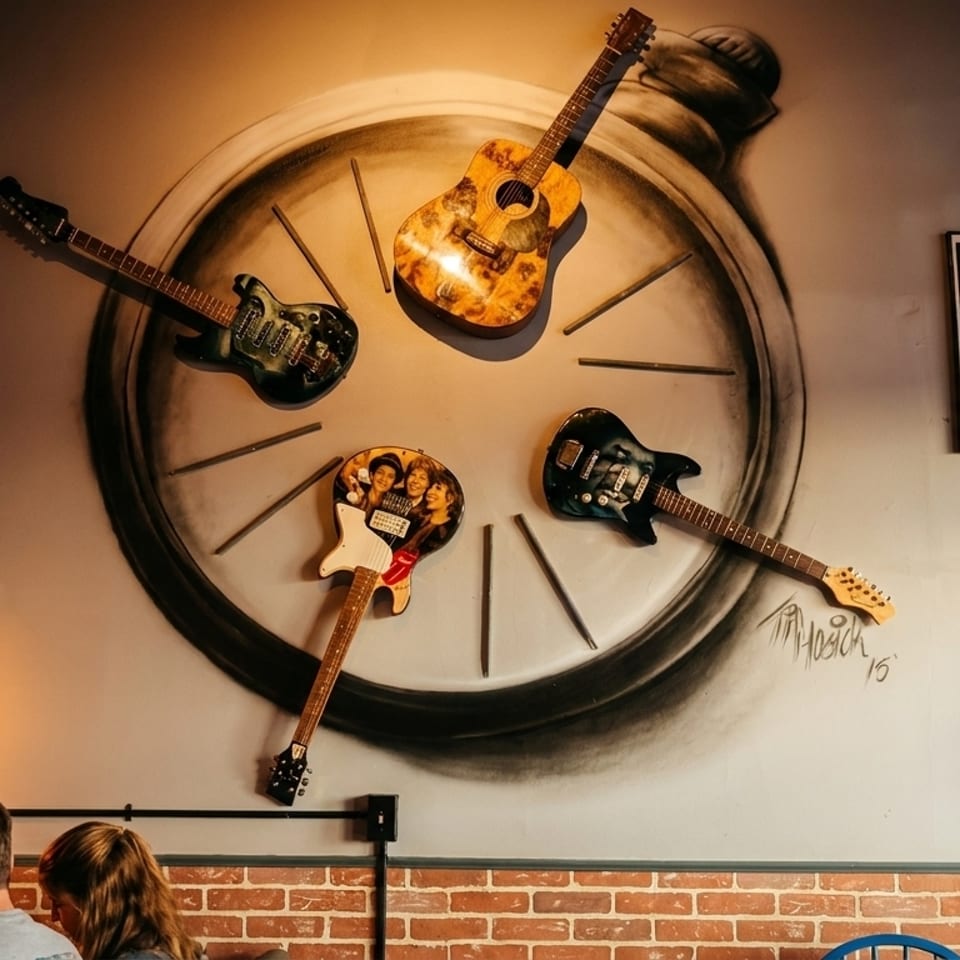 Guitars and music posters adorn a restaurant wall above patrons, creating a rock-and-roll ambiance.